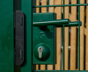 Gate slam plate on green metal gate with lock and gate hardware at farm