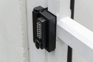 heavy duty keypad lock with code installed on a white wooden timber frame garden driveway gate.