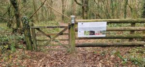 Weathered wooden gate and fence in woodlands at private estate with sign for Butterwell Farm sign.