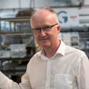Man with glasses and in white shirt looking at camera and smiling
