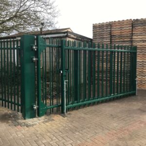 Large green metal gate at industrial compound. Gate is fitted with heavy duty hinges and dropbolt