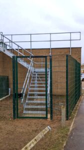 Hospital gate in front of metal stair case. Metal gate with gate hardware and locks installed.