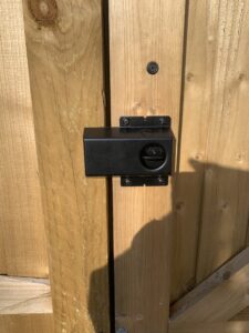 Security shroud and gate latch lock on softwood timber garden gate.