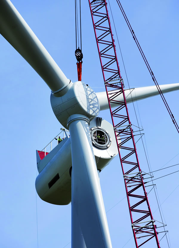 Wind turbine blades being lifted by a crane to top of turbine
