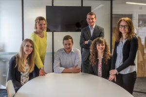 2017 team picture of 6 people standing around a white desk