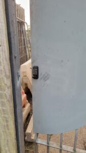 digital keypad keyless lock installed on grey metal gate with security shroud